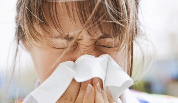 Young blonde female blowing her nose