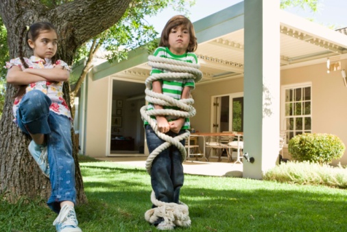 Boy tied up by sister outdoors