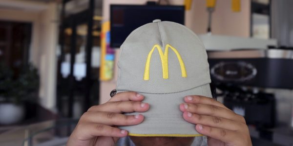 The logo of McDonald's is seen on the cap of a staff member as she adjusts it at a McDonald's restaurant in Sao Paulo February 24, 2015. Brazilian unions have filed suit alleging that the largest operator of McDonald's restaurants in Latin America violates Brazil's labor laws, a case that could lead to fines of up to 30 percent of annual sales. According to the suit filed on Monday in Brazil's federal labor court in Brasilia, violations committed by Arcos Dorados Holdings Inc. amount to "social dumping" and help McDonald's Corp. illegally undercut competitors and boost profit. Arcos Dorados said in a statement that it has not yet seen the content of the lawsuit but defended its labor practices, saying the company "is absolutely confident in its labor practices and in the meeting of all the norms and laws it is subject to in all the places it works." REUTERS/Nacho Doce (BRAZIL - Tags: BUSINESS EMPLOYMENT SOCIETY)