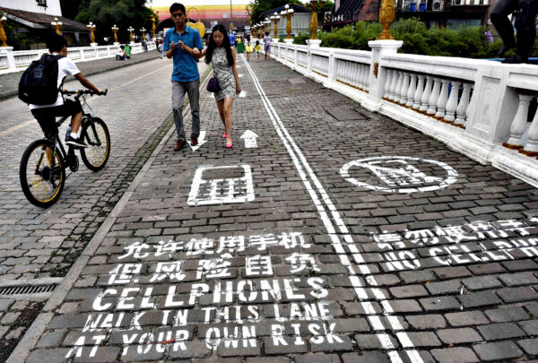 A man rides his bicycle as people walk on the "first mobile phone sidewalk in China", which was recently installed at a tourism area in Chongqing municipality...A man rides his bicycle as people walk on the "first mobile phone sidewalk in China", which was recently installed at a tourism area in Chongqing municipality, September 13, 2014. The mobile phone sidewalk in Chongqing was divided into two sides -- one was written with "Cellphones walk in this lane at your own risk" while the other with "No cellphones", as an attempt to reduce pedestrian incidents, local media reported. Picture taken September 13, 2014. REUTERS/China Daily (CHINA - Tags: SOCIETY SCIENCE TECHNOLOGY) CHINA OUT. NO COMMERCIAL OR EDITORIAL SALES IN CHINA
