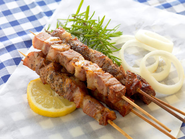greek pork souvlaki served in a traditional way, on a baking paper with onion rings and lemon