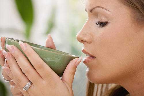 Closeup portrait of beautiful girl drinking tea, side view.