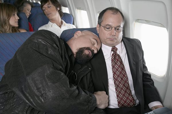 Businessman Sitting in an Aeroplane Trapped by a Man Sleeping by His Side