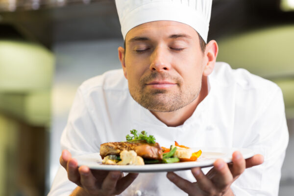 Closeup of a male chef with eyes closed smelling food in the kitchen