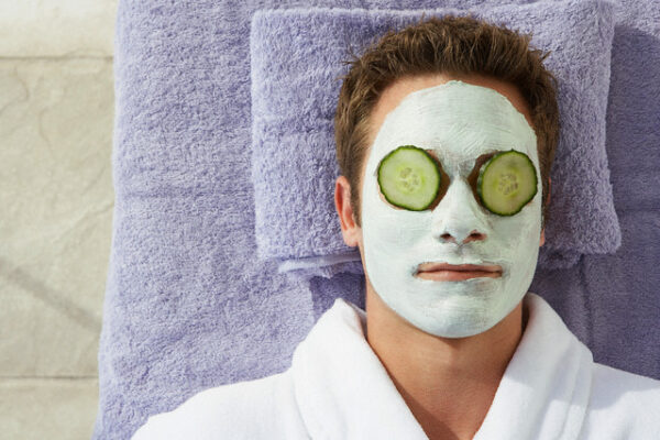 Man in facial mask with cucumber slices over his eyes --- Image by © Felix Wirth/Corbis
