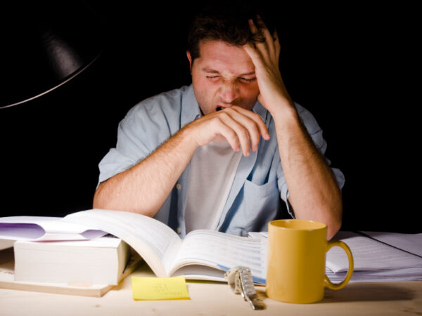 Young Man Yawning tired while Studing at Night