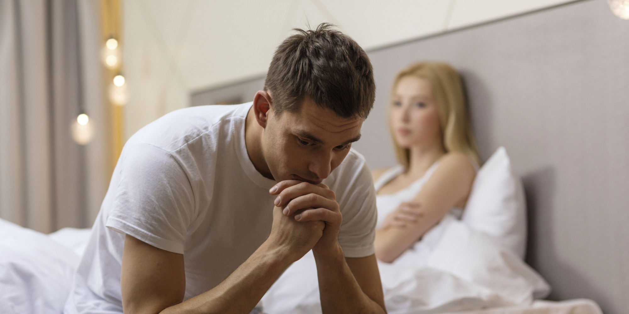 man sitting on the bed with disappointed woman