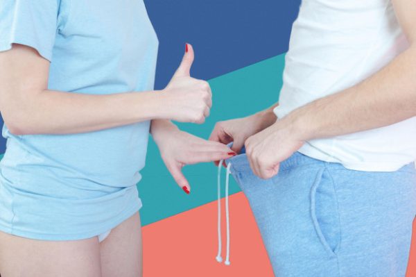 EJFA3Y Woman pointing thumb up in direction of male genitalia while man holds open underwear and showing his penis. Question of impoten