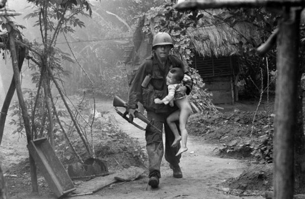 A U.S. infantryman from A Company, 1st Battalion, 16th Infantry carries a crying child from Cam Xe village after dropping a phosphorous grenade into a bunker cleared of civilians during an operation near the Michelin rubber plantation northwest of Saigon, August 22, 1966. A platoon of the 1st Infantry Division raided the village, looking for snipers that had inflicted casualties on the platoon. GIs rushed about 40 civilians out of the village before artillery bombardment ensued. (AP Photo/Horst Faas)