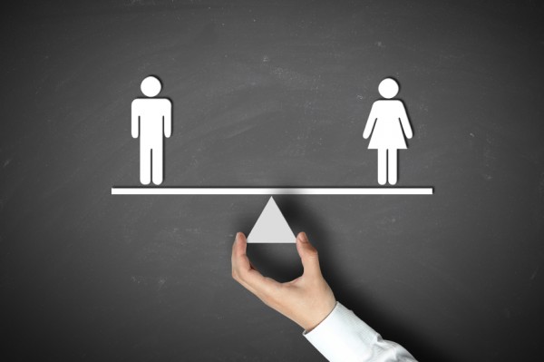 Male equals female concept with businessman hand holding against blackboard background.