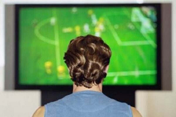 Man watching sports football game on television, rear view