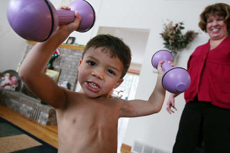 Liam Hoekstra, 3, has myostatin deficiency, which increases his muscle mass and reduces his body fat. He is pictured holding five pound weights with his mother, Dana Hoekstra, inside their Roosevelt Park home Thursday. (Date shot- 12/11/08)