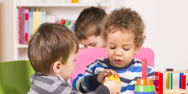 Toddlers helping and sharing in the playroom