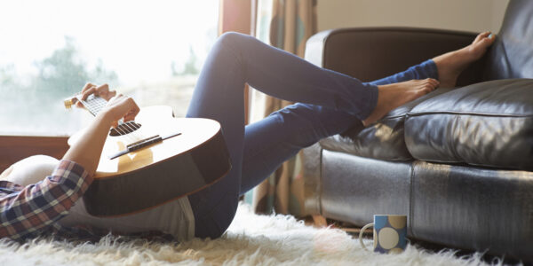 Woman at home playing guitar.