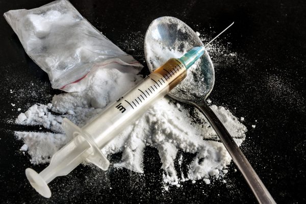 Drug syringe and cooked heroin on spoon