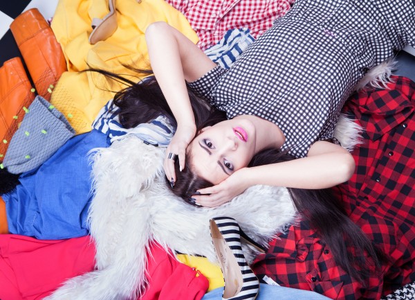 Stressed young woman lying down on a pile of clothes