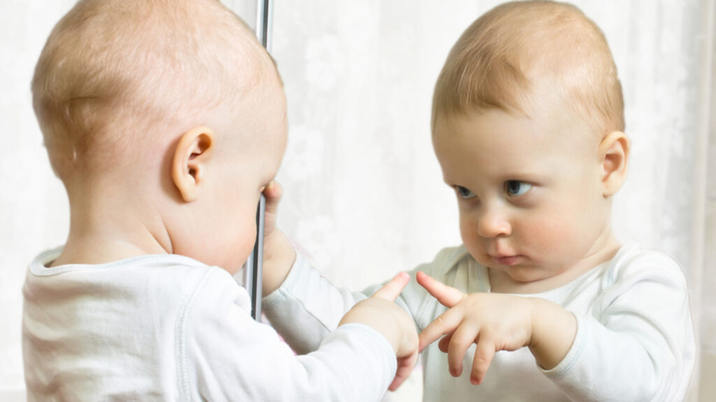 Ten month boy stands before the mirror; Shutterstock ID 129088694; PO: today-parents