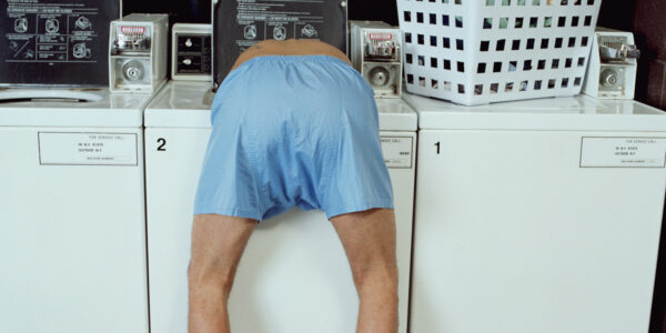 Man leaning in washing machine low section, rear view