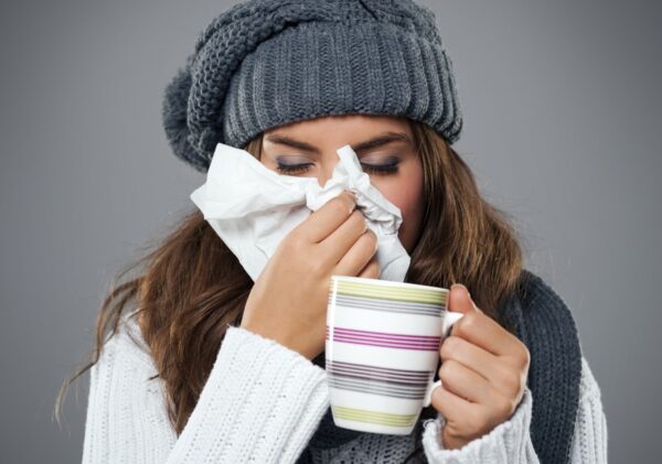 Young woman having flu and blowing her nose at handkerchief