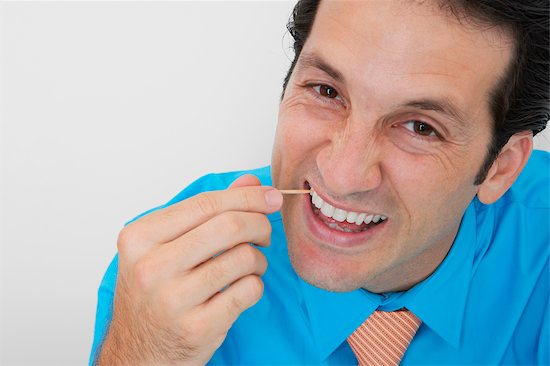 678-02678267 © Masterfile Royalty Free Model Release: Yes Property Release: No Portrait of a businessman picking his teeth in an office