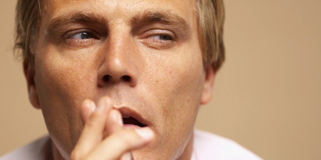Close-up of a young businessman with his hands in front of his mouth