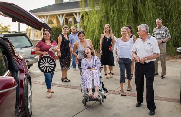 This July 24, 2016 photo provided by Niels Alpert, Betsy Davis, center, is accompanied by friends and family for her first ride in a friends new Tesla to a hillside to end her life during a "Right To Die Party" in Ojai, Calif.  In early July, Davis emailed her closest friends and family to invite them to a two-day celebration, telling them: "These circumstances are unlike any party you have attended before, requiring emotional stamina, centeredness, and openness.  And one rule: No crying. " The 41-year-old woman diagnosed with ALS,  held the party to say goodbye before becoming one of the first California residents to take life-ending drugs under a new law that gave such an option to the terminally ill. (Niels Alpert via AP)