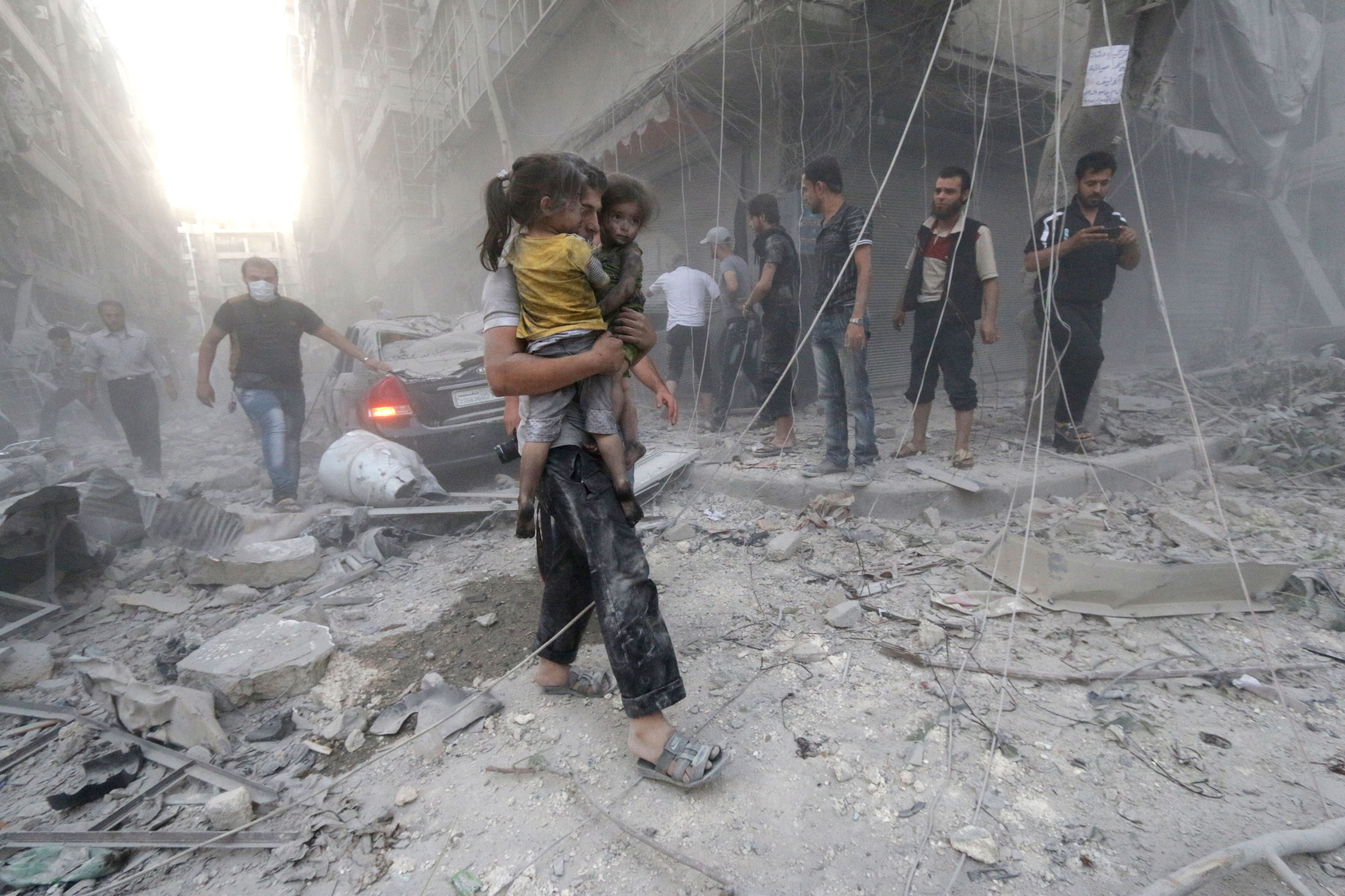 A Syrian man carries two girls covered with dust following a reported air strike by government forces on July 9, 2014 in the northern city of Aleppo. According to the Syrian Observatory for Human Rights, by May some 2,000 civilians including 500 children had been killed in the daily air strikes, which rights groups have condemned as a "war crime" for failing to discriminate between military and civilian targets. AFP PHOTO /AMC/ZEIN AL-RIFAI (Photo credit should read ZEIN AL-RIFAI/AFP/Getty Images)