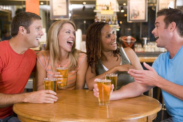 Group of young friends drinking and laughing in a bar