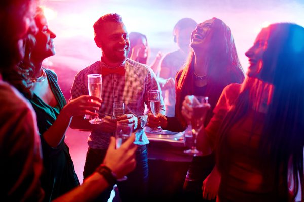 Ecstatic friends with champagne talking at party in night club