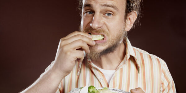 Mature man eating salad, close-up, portrait