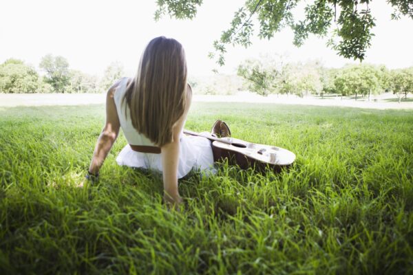 Teenage girl on the grass with a guitar