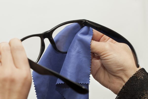 Woman trying to clean spectacles