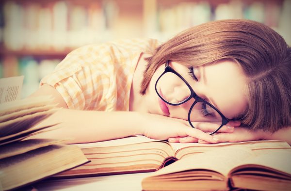 tired student girl with glasses sleeping on the books in the library ** Note: Shallow depth of field