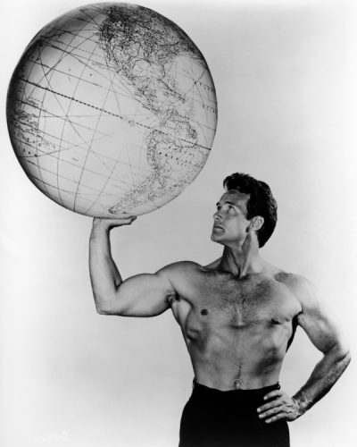 American bodybuilder and actor Steve Reeves (1926 - 2000) holding up a large globe, circa 1960. (Photo by Silver Screen Collection/Getty Images)