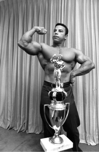 Chris Dickerson, 30, flexes his biceps as he poses with his Mr. America 1970 trophy in his New York City apartment on July 10, 1970. He won the contest in Los Angeles, Ca., June 14, 1970. (AP Photo/Marty Lederhandler)