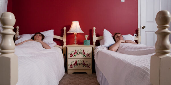 Young couple lying awake in single beds