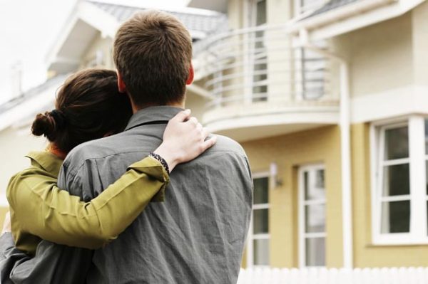 couple in front of one-family house in modern residential area