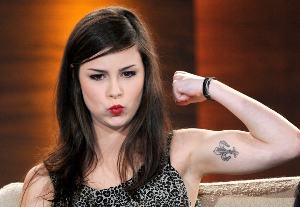 German singer Lena Meyer-Landrut shows her tattoo during the TV show "Wetten, dass..?" (Let's Make a Bet)  in the northern German city of Hanover on November 6, 2010. AFP PHOTO POOL / PETER STEFFEN (Photo credit should read PETER STEFFEN/AFP/Getty Images)