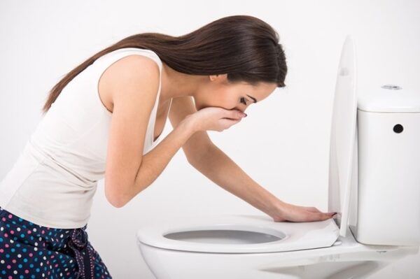 Young woman vomiting into the toilet bowl in the early stages of pregnancy or after a night of partying and drinking.
