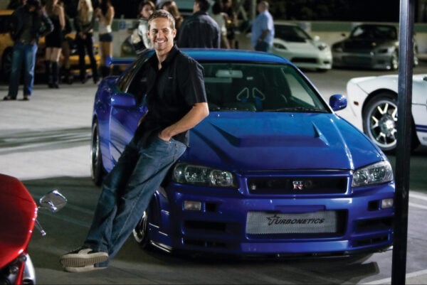 PAUL WALKER as agent Brian O'Conner leans against his 1998 Nissan Skyline GTR in the ultimate chapter of the franchise built on speed--"Fast & Furious".