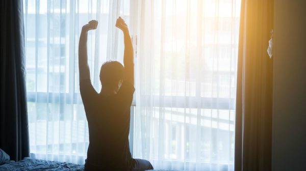 man waking up stretching arms after good night of sleep 7 COISAS IRRITANTES QUE ACONTECEM E AS EXPLICAÇÕES POR TRÁS DELAS man waking up stretching arms after good night of sleep