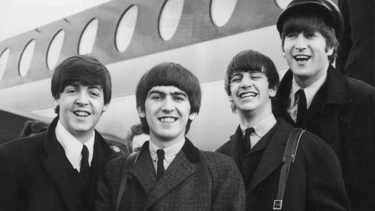 Foto clássica dos Beatles em formação original durante sessão fotográfica ou apresentação ao vivo