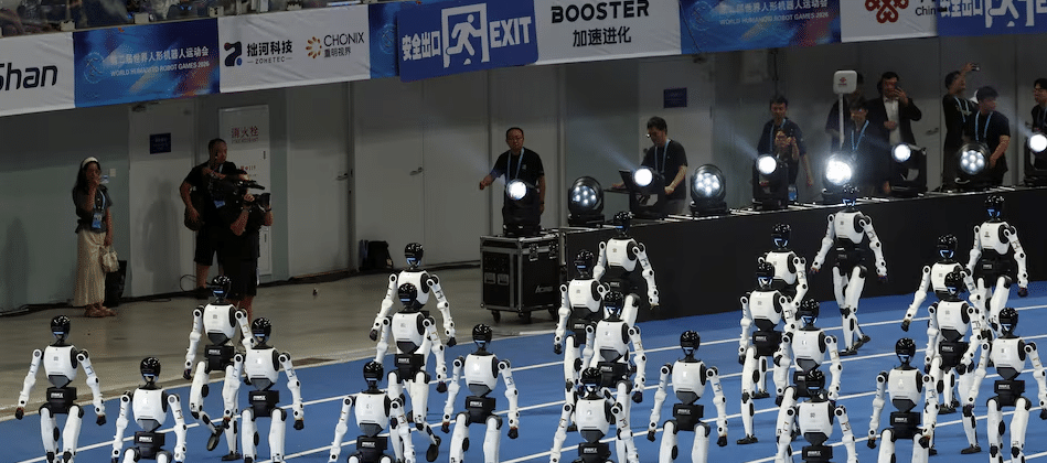 Espectadores assistem aos robôs humanoides Tiangong desfilarem em formação durante a cerimônia de abertura da segunda edição dos Jogos Mundiais de Robôs Humanoides, no Circuito Nacional de Patinação de Velocidade, em Pequim, China, em 22 de agosto de 2026. Foto: REUTERS/Florence